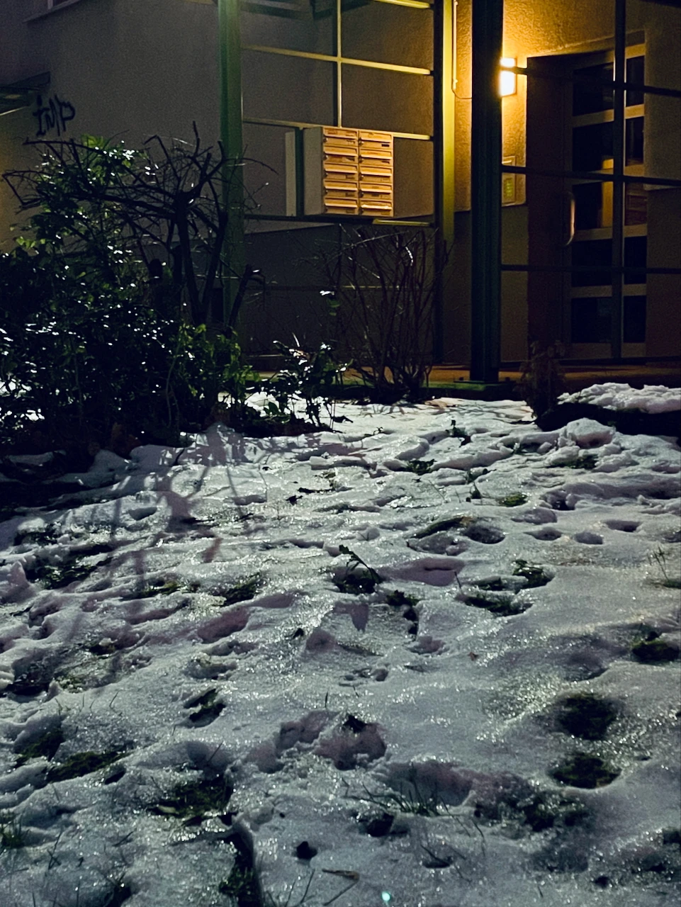 A picture of a mailbox in front of a building in a snowy street